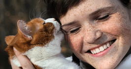 cat licking face of smiling woman